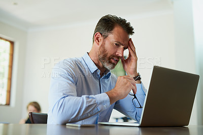 Buy stock photo Shot of a mature businessman looking stressed while using a laptop to work from home
