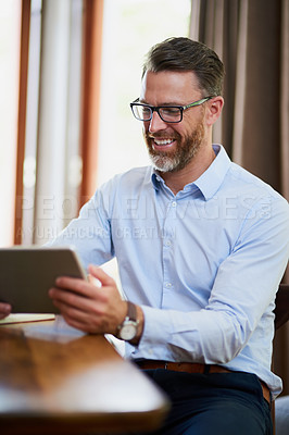 Buy stock photo Shot of a mature businessman using a digital tablet to work from home