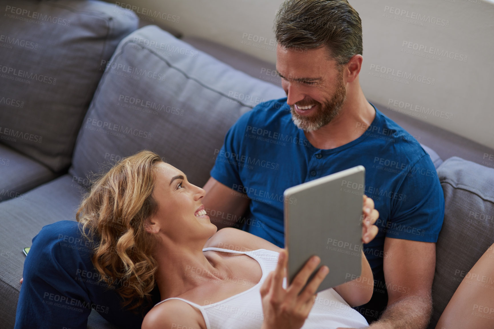 Buy stock photo Shot of a happy middle aged couple using a digital tablet together on the sofa at home