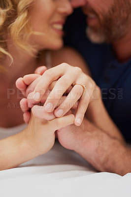 Buy stock photo Cropped shot of a happy middle aged couple holding hands and relaxing in bed together