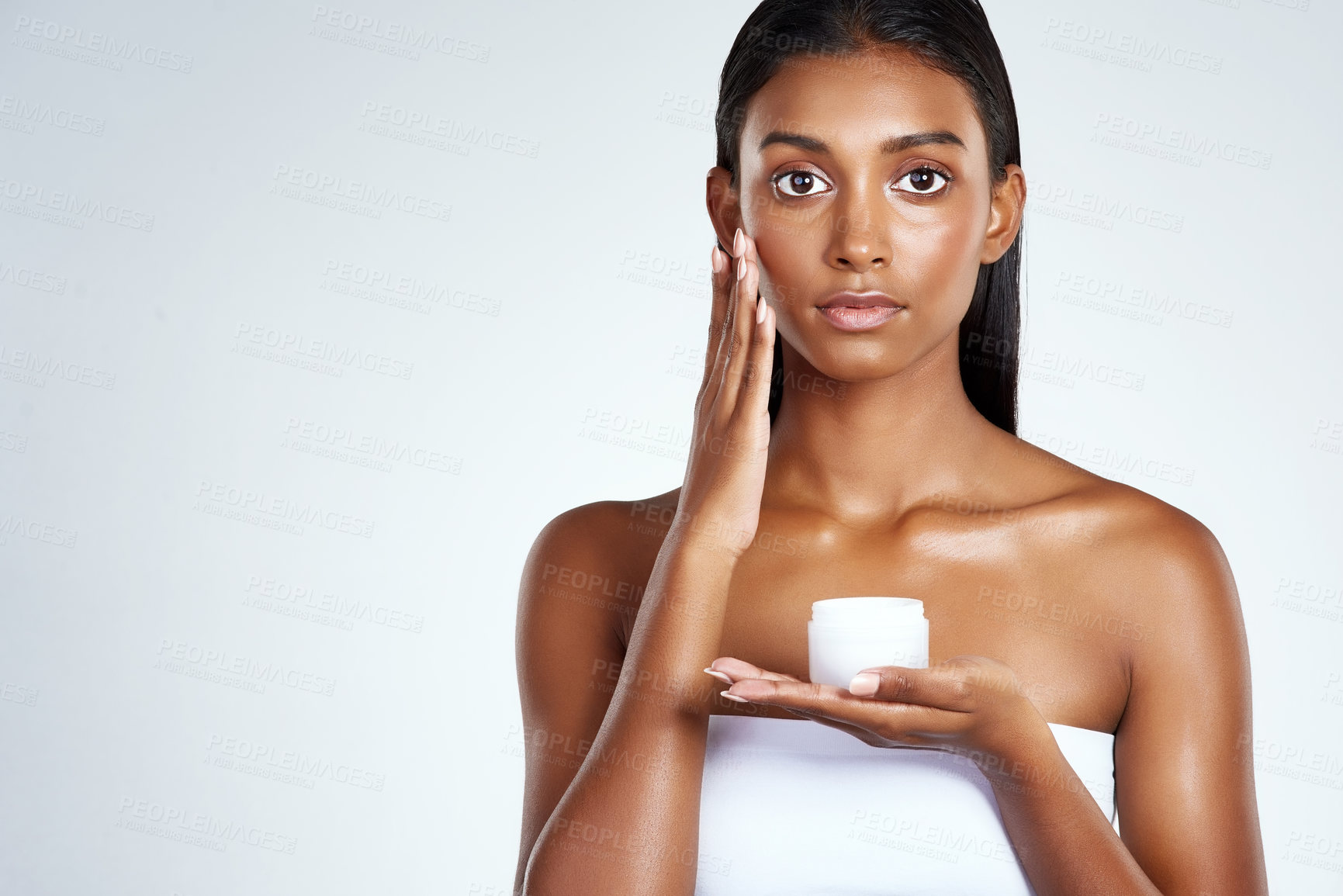 Buy stock photo Indian woman, portrait and skincare product in studio as moisturizing lotion, application or dermatology. Female person, hand and white background with wellness cream or sunscreen, mask or mockup