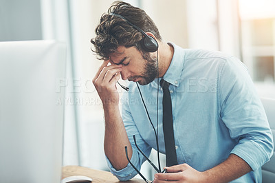 Buy stock photo Shot of a young man experiencing stress while working in a call center