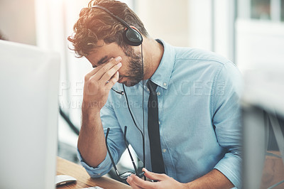 Buy stock photo Shot of a young man experiencing stress while working in a call center