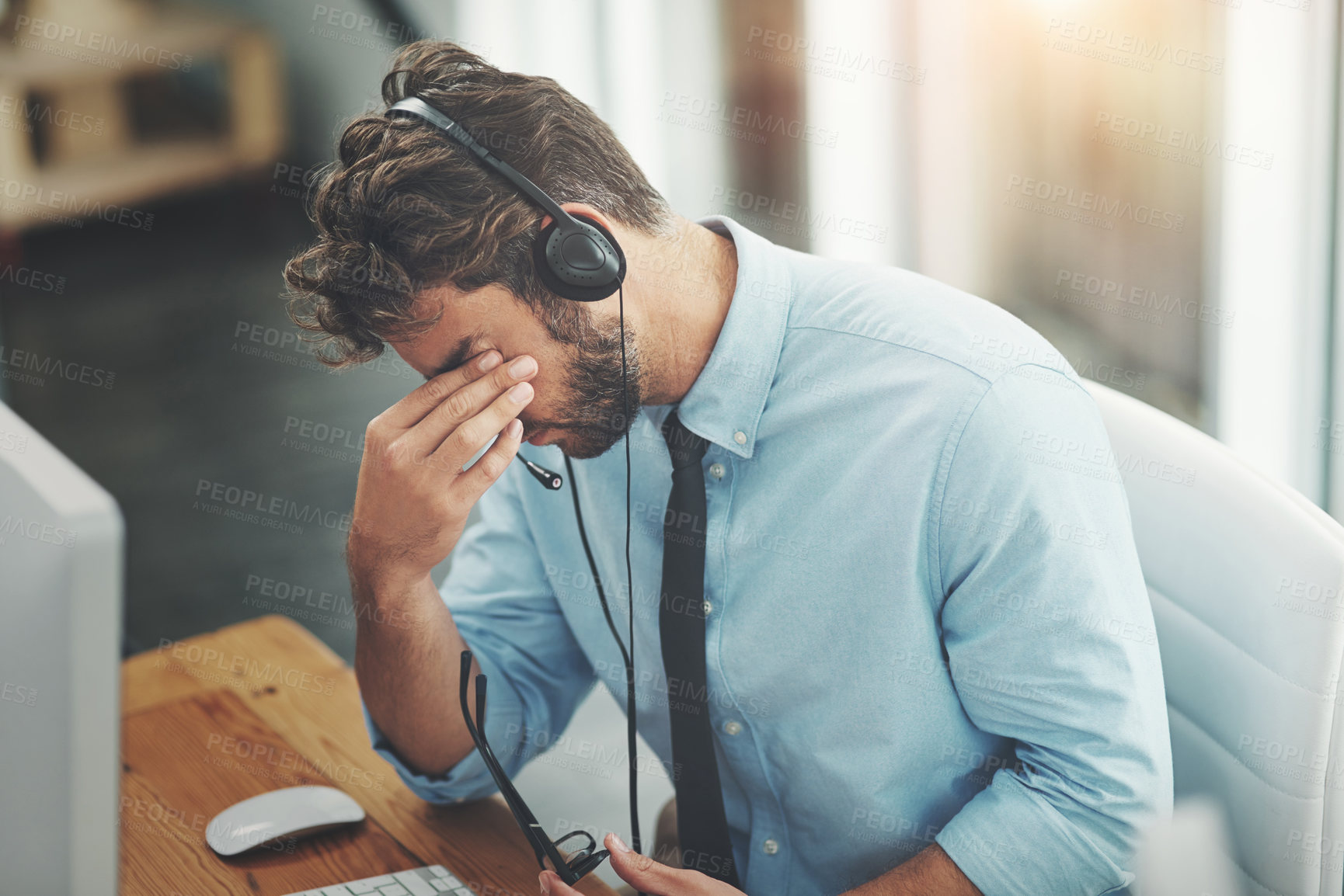 Buy stock photo Shot of a young man experiencing stress while working in a call center
