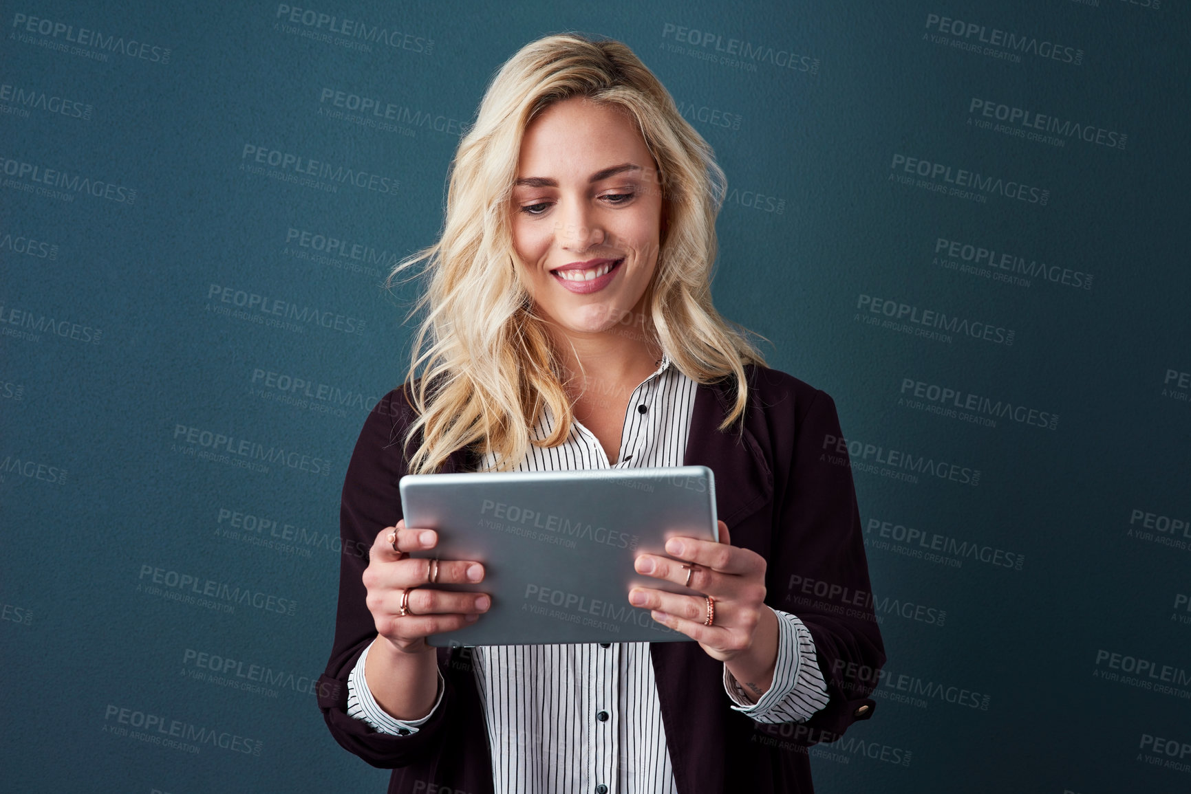 Buy stock photo Studio shot of a beautiful young businesswoman using a tablet against a blue background