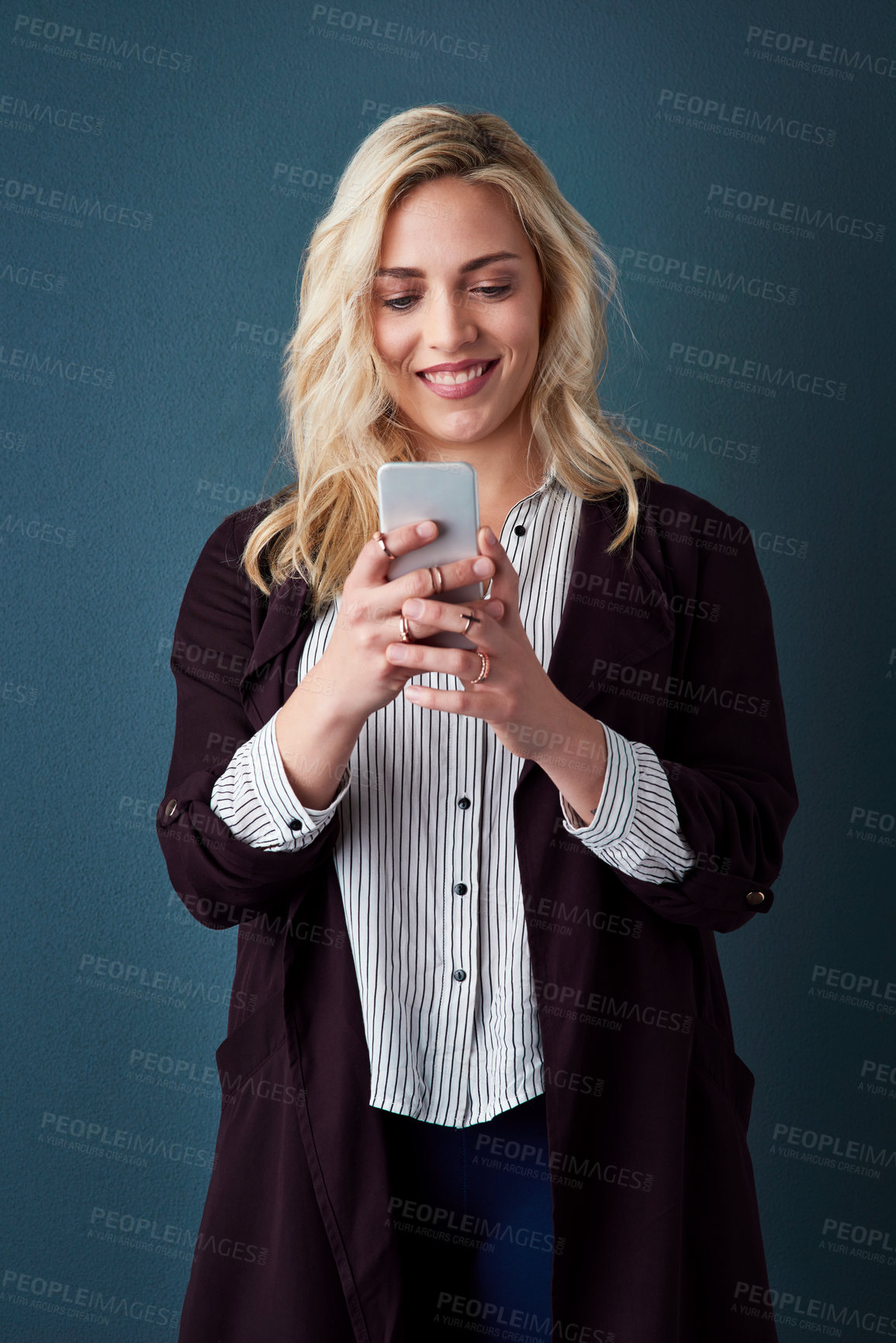 Buy stock photo Studio shot of a beautiful young businesswoman using a cellphone against a blue background