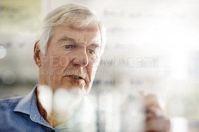 Buy stock photo Cropped shot of a senior businessman writing down ideas with a pen marker on a glass wall in the office