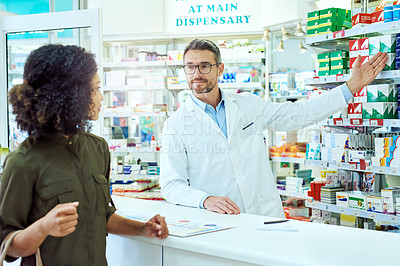 Buy stock photo Cropped shot of a handsome mature male pharmacist helping a female customer in the pharmacy