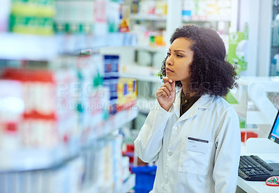 Buy stock photo Cropped shot of an attractive young female pharmacist looking for medication in a pharmacy
