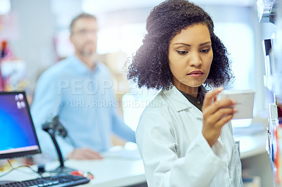 Buy stock photo Cropped shot of an attractive young female pharmacist looking for medication in a pharmacy