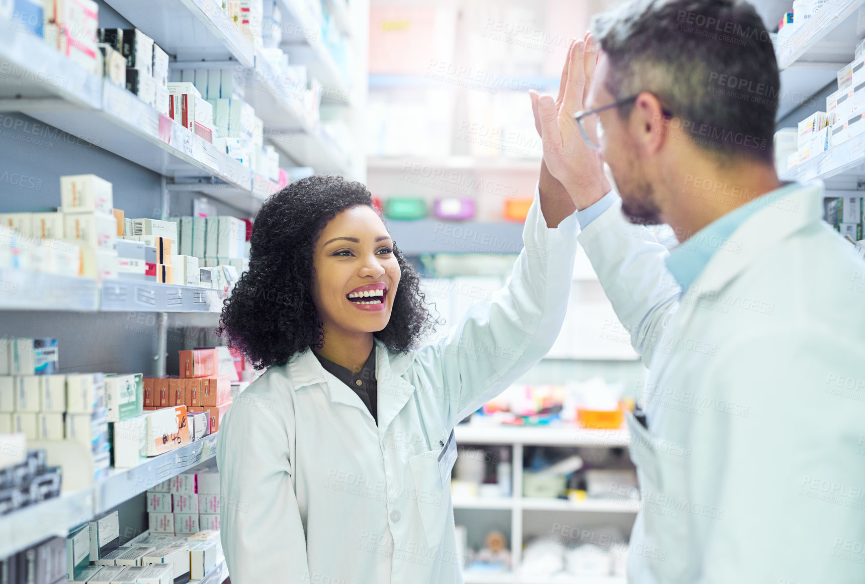 Buy stock photo Shot of a mature man and young woman giving each other a high five while working in a pharmacy