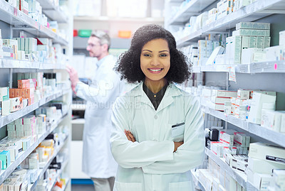 Buy stock photo Portrait of a confident young woman working in a pharmacy with her colleague in the background