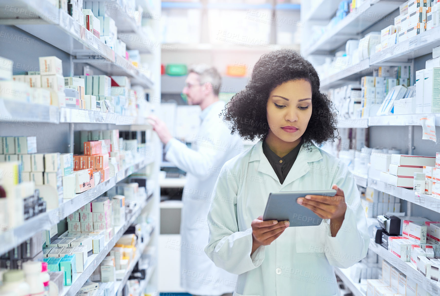 Buy stock photo Shot of a young woman using a digital tablet to do inventory in a pharmacy