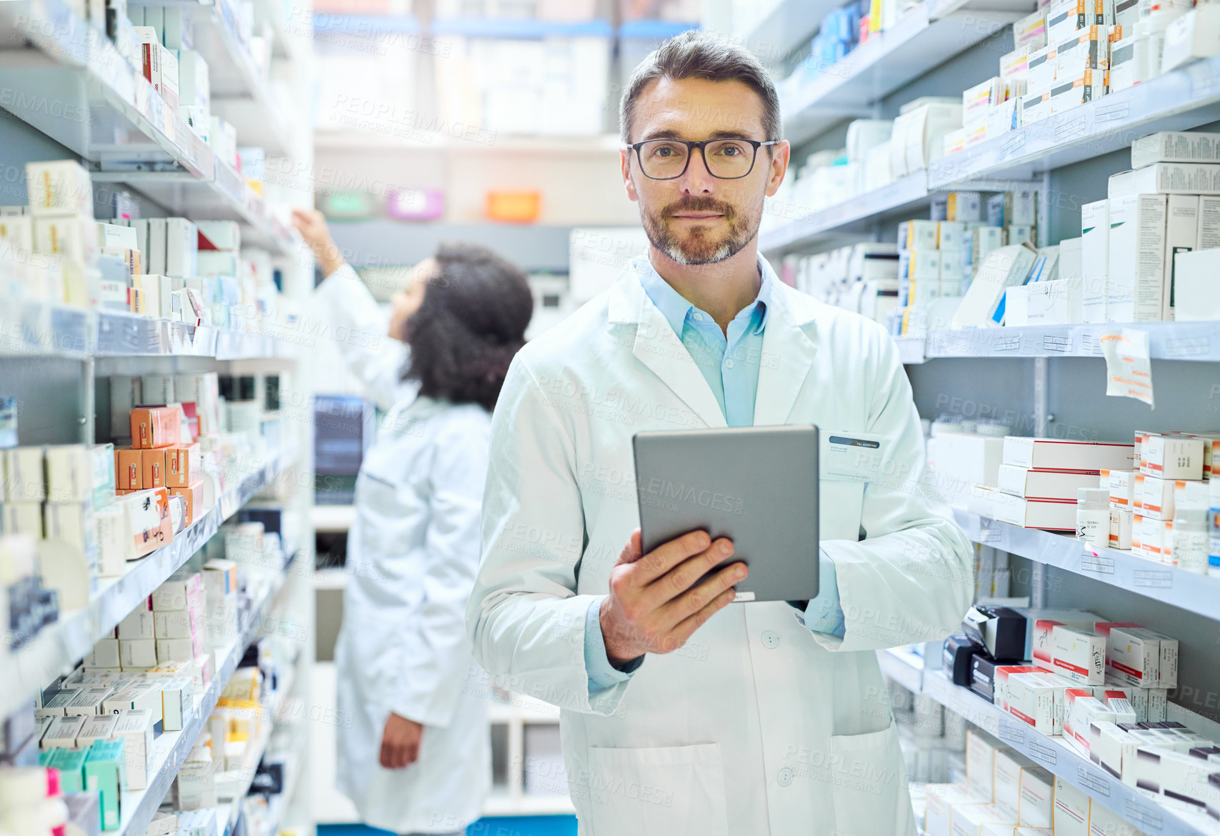 Buy stock photo Shot of a mature man using a digital tablet to do inventory in a pharmacy