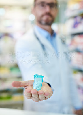 Buy stock photo Shot of a mature man extending his arm to show a bottle of pills at a pharmacy