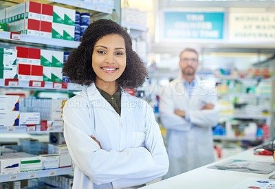 Buy stock photo Shot of a young woman working at the counter of a pharmacy with her colleague in the background