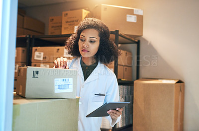 Buy stock photo Shot of a young woman using a digital tablet while doing inventory in the storeroom of a pharmacy