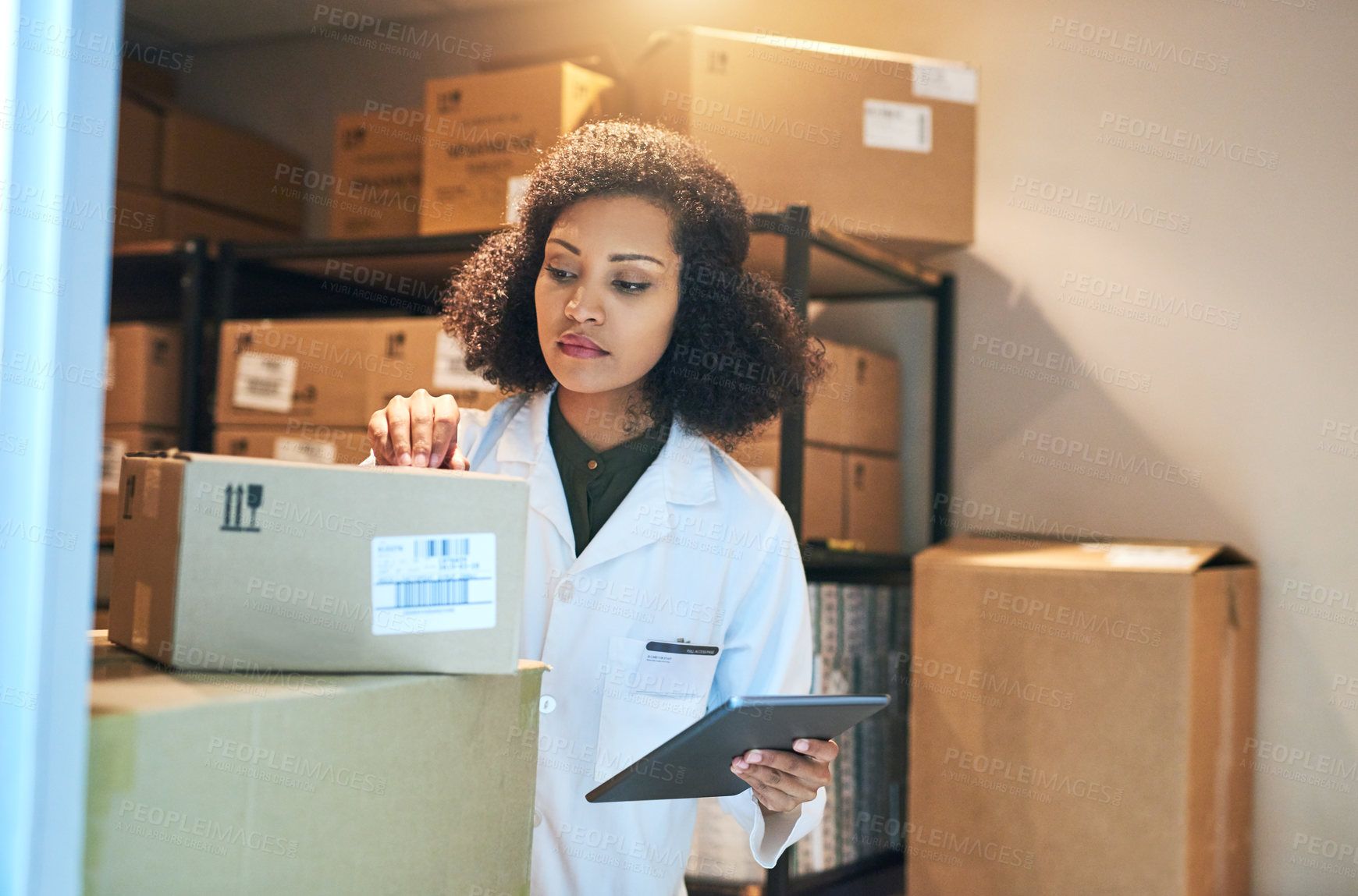 Buy stock photo Shot of a young woman using a digital tablet while doing inventory in the storeroom of a pharmacy