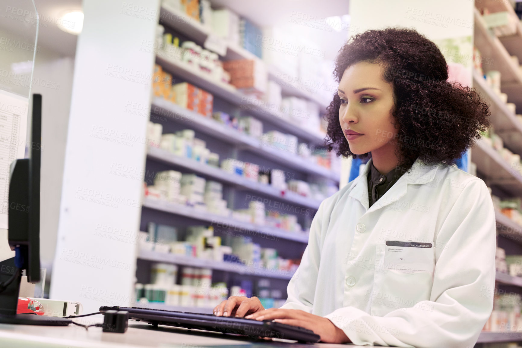 Buy stock photo Cropped shot of a pharmacist working on a computer in a pharmacy