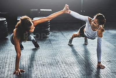 Buy stock photo Shot of two young women giving each other a high five while doing push ups at the gym