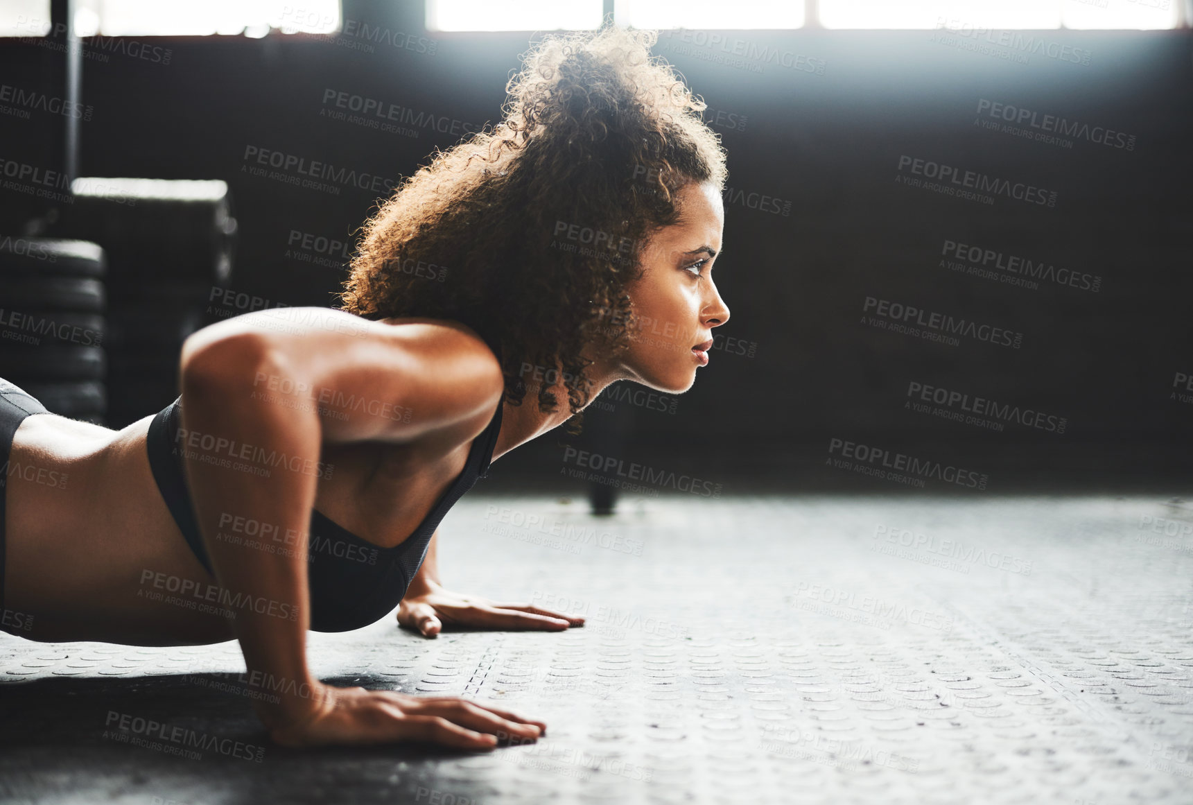 Buy stock photo Shot of a young woman doing pushups in a gym