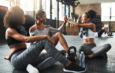 Buy stock photo Shot of young women giving each other a high five while taking a break at the gym