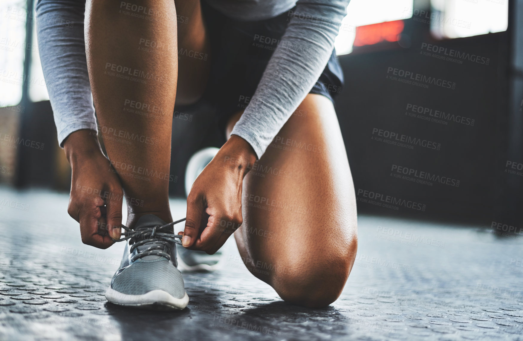 Buy stock photo Cropped shot of a woman tying her shoelaces in a gym