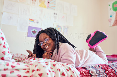 Buy stock photo Shot of an adorable little girl using a cellphone on her bed in her bedroom