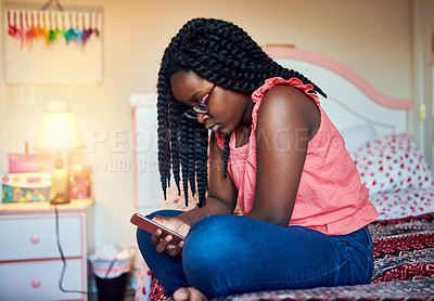 Buy stock photo Cropped shot of an adorable little girl sitting on her bed using a cellphone in her bedroom