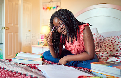 Buy stock photo Shot of an adorable little girl doing her homework on her bed in her bedroom