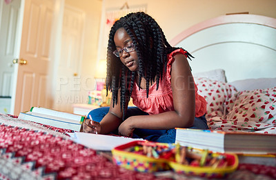 Buy stock photo Shot of an adorable little girl doing her homework on her bed in her bedroom