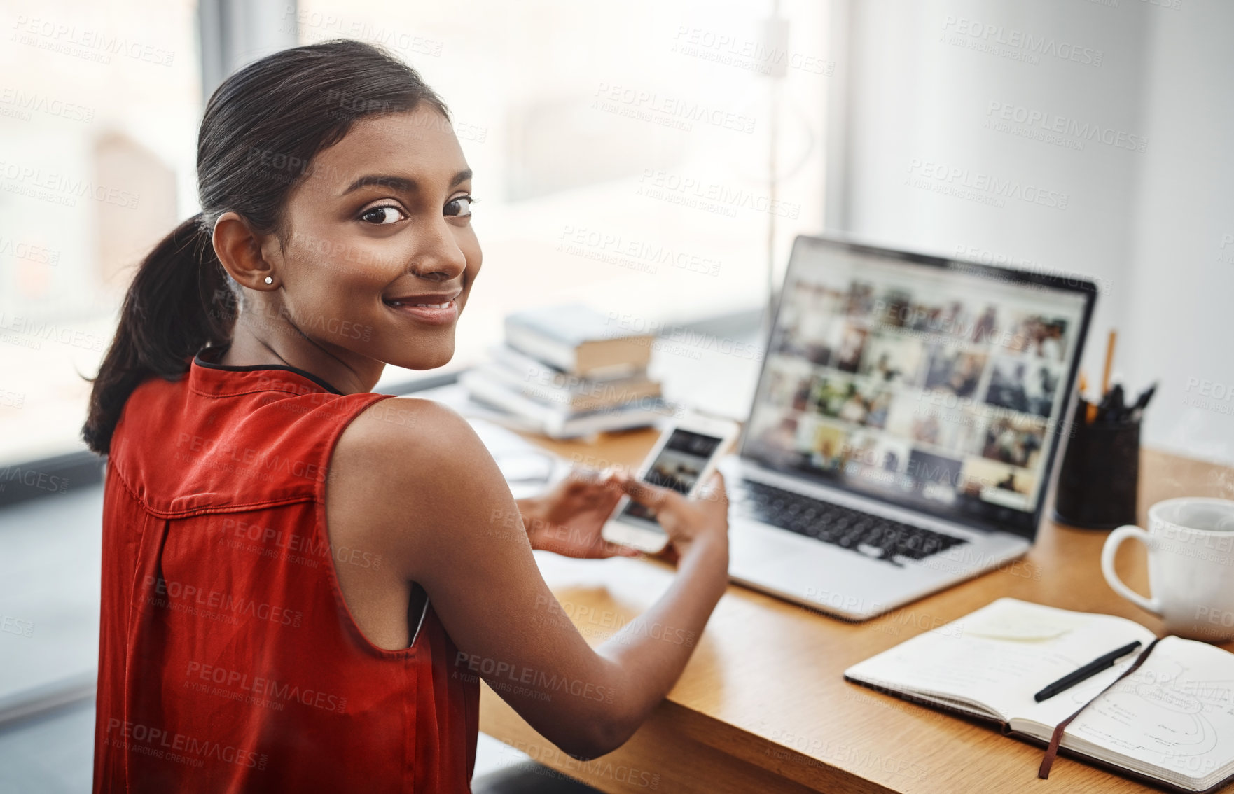 Buy stock photo Business woman, portrait and smile with a phone and laptop at desk for media, research and creative work or blog. Happy Indian female entrepreneur with a smartphone and internet for communication