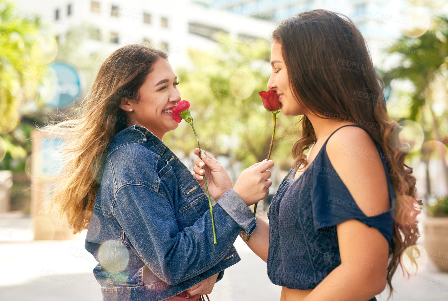 Buy stock photo Cropped shot of two female best friends being smelling roses in the city