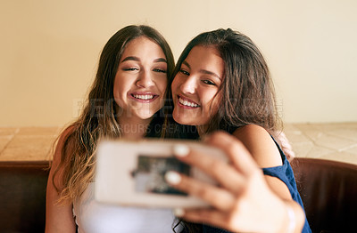 Buy stock photo Cropped shot of two attractive young women taking selfies in their local cafe