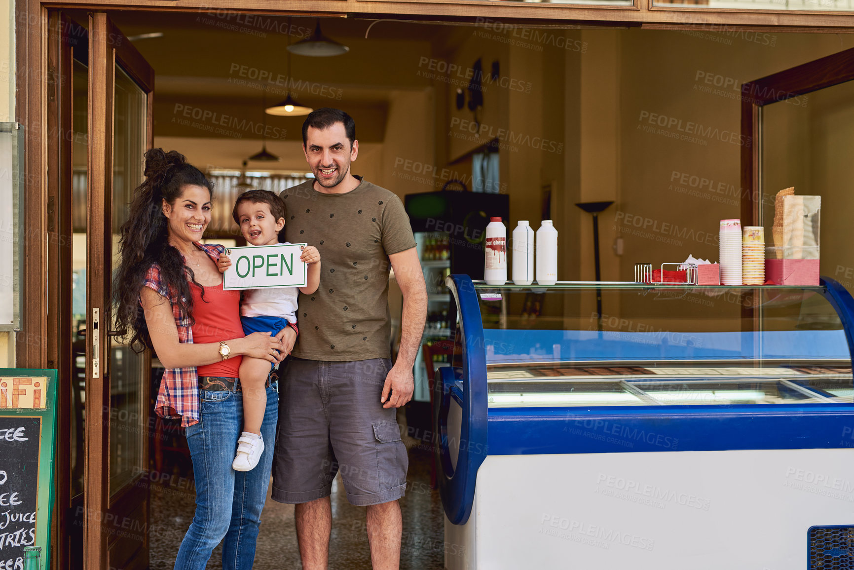 Buy stock photo Cropped portrait of an affectionate family of three standing in the entrance way to their ice cream shop