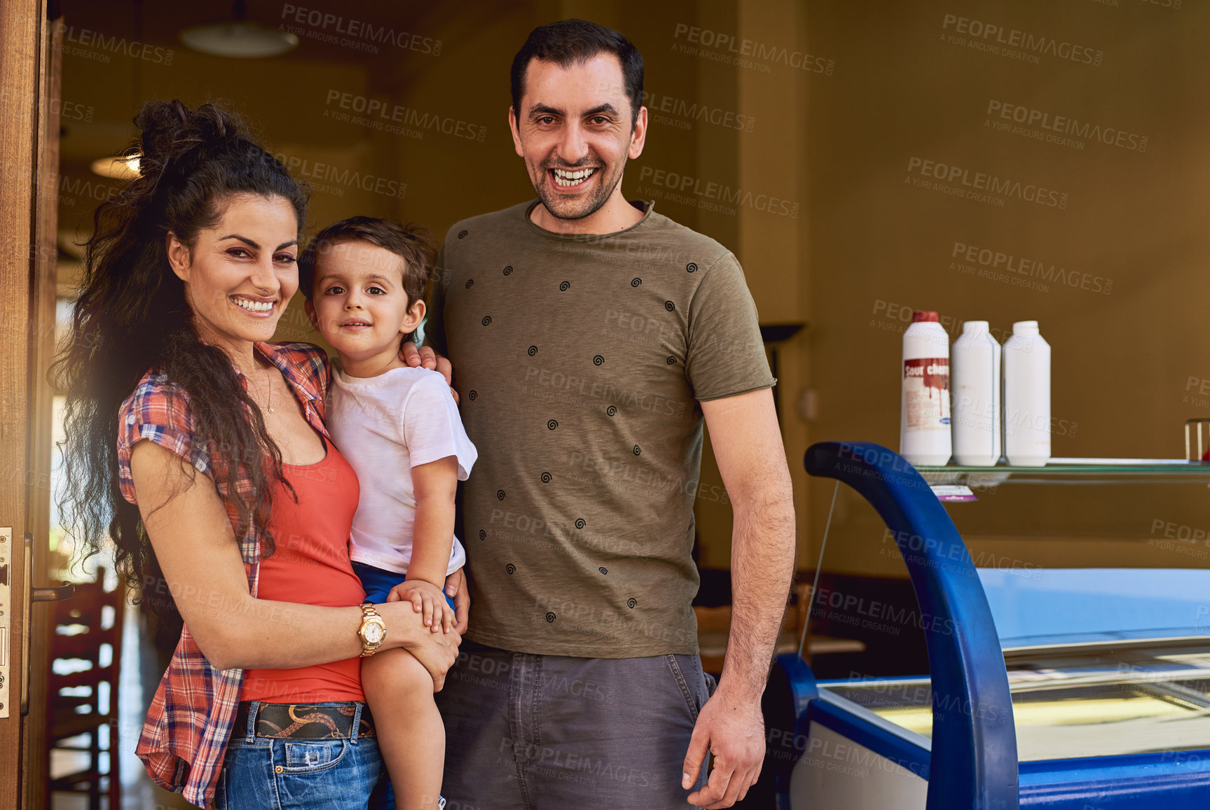 Buy stock photo Cropped portrait of an affectionate family of three standing in the entrance way to their ice cream shop