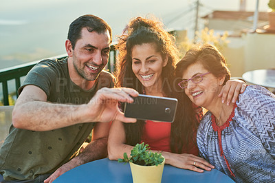 Buy stock photo Cropped shot of an affectionate family of three taking selfies while sitting outside