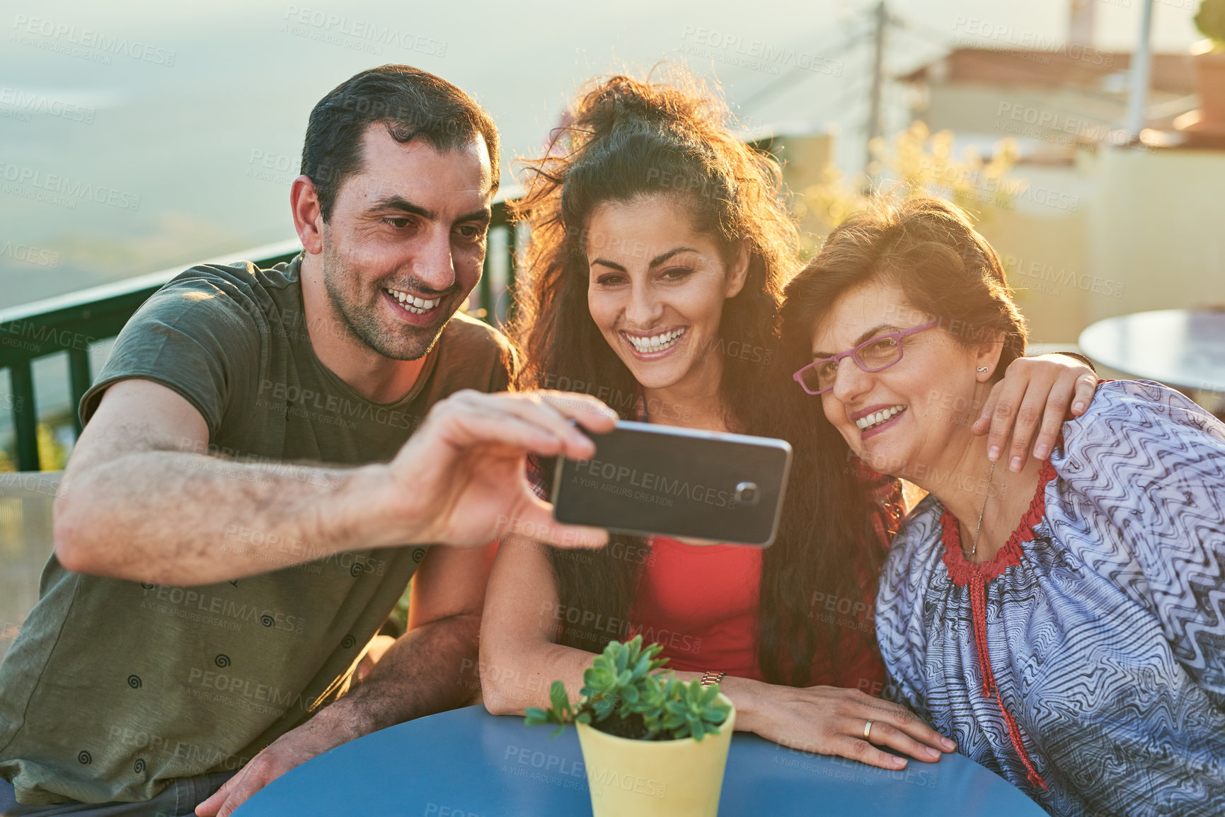 Buy stock photo Cropped shot of an affectionate family of three taking selfies while sitting outside