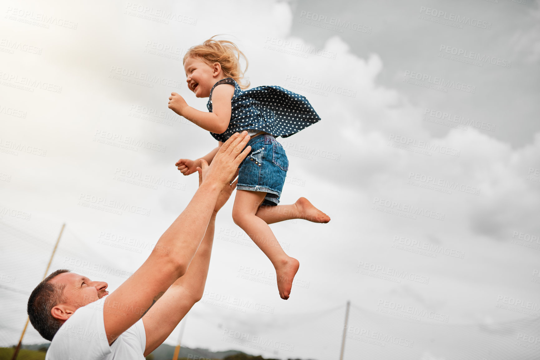 Buy stock photo Cropped shot of a mature man tossing his young daughter into the air and then catching her outside