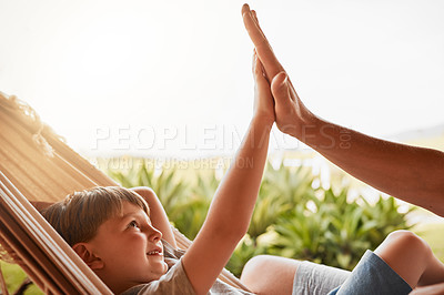 Buy stock photo Cropped shot of an unrecognizable man and his young son high fiving while lying outside on a hammock