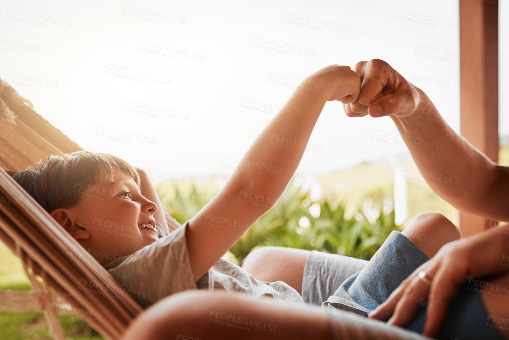 Buy stock photo Cropped shot of an unrecognizable man and his young son fist bumping while lying outside on a hammock