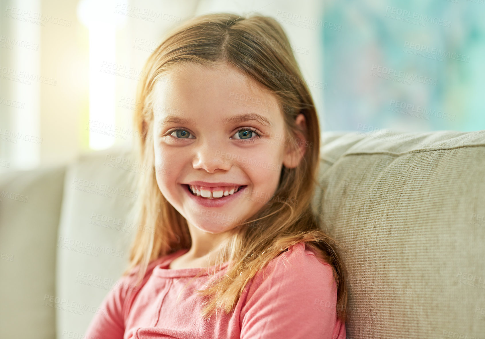 Buy stock photo Cropped portrait of an adorable little girl sitting on a sofa at home