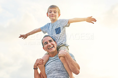 Buy stock photo Low angle shot of a mature man carrying his son on his shoulders outside