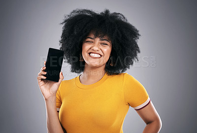 Buy stock photo Studio shot of an attractive young woman posing with a cellphone against a grey background