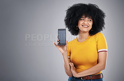 Buy stock photo Studio shot of an attractive young woman posing with a cellphone against a grey background