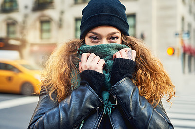 Buy stock photo Shot of a woman covering her mouth with her scarf while out in the city