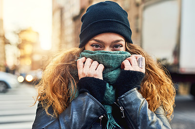 Buy stock photo Shot of a woman covering her mouth with her scarf while out in the city