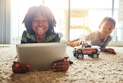 Buy stock photo Shot of a little boy using his digital tablet while his brother plays in the background