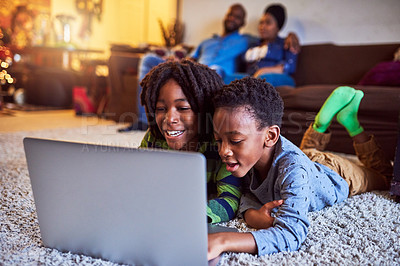 Buy stock photo Shot of two little boys using a laptop together with their parents sitting in the background