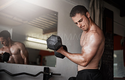 Buy stock photo Cropped shot of a handsome and muscular young man working out with a dumbbell in the gym